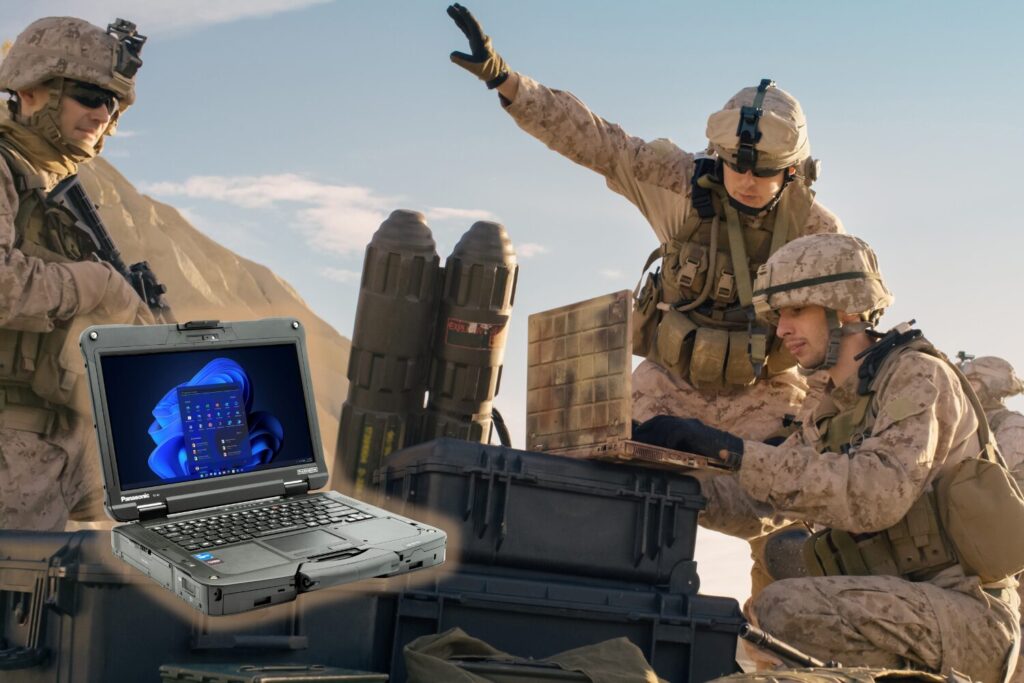 Soliders in a desert environment gathered round a computer